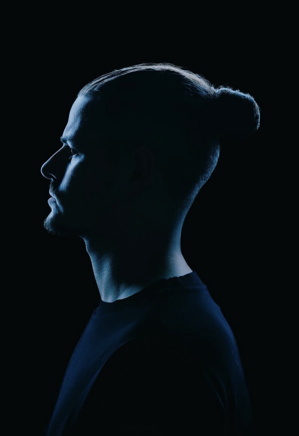 Dennis Reif in blue light, with a second skull-lit portrait appearing through distorted bands.